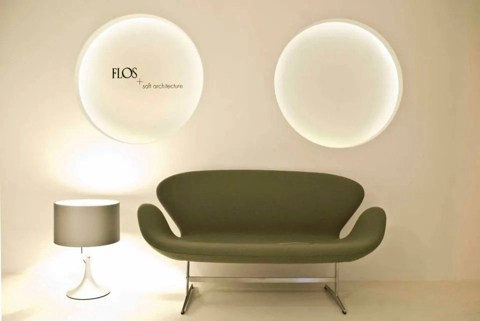 The Lightology Lab showroom: two round Flos wall lights above a green sofa and a table lamp