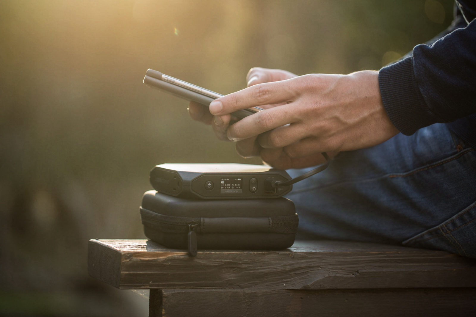 Hands holding a phone and an Omni at sunset